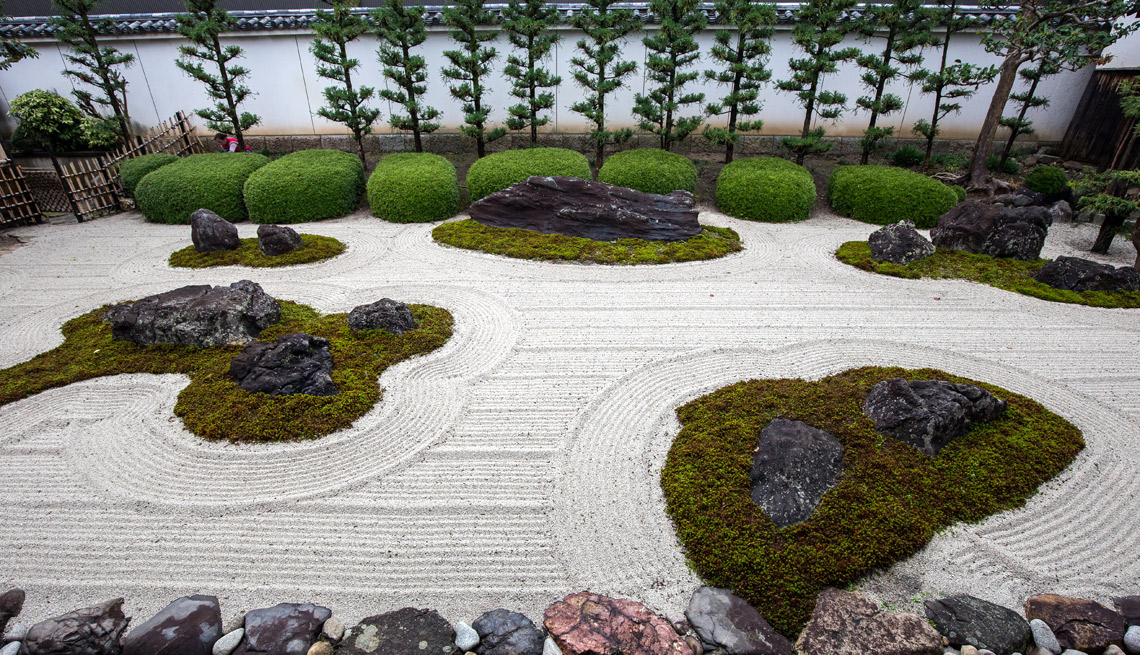Jardín zen con rocas, musgo y árboles.