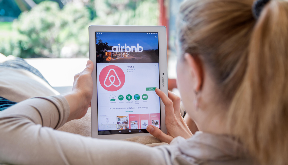 Mujer bajando la aplicación de Airbnb en una tableta electrónica