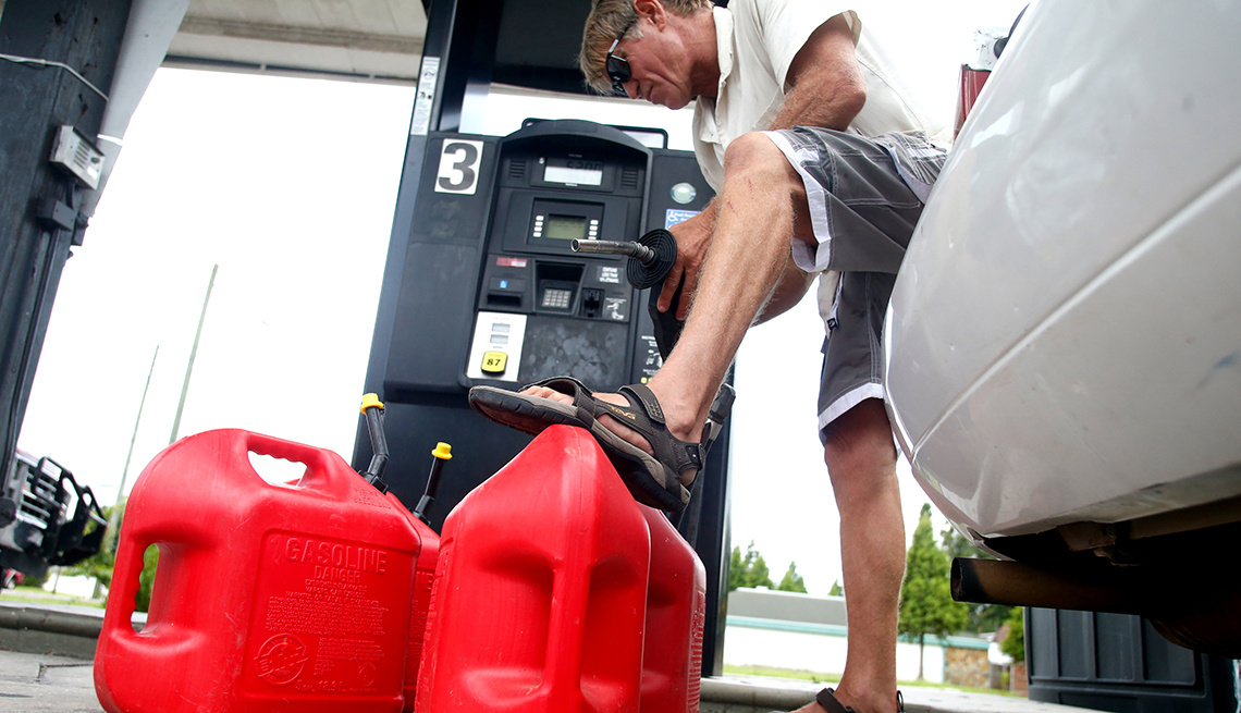 Un hombre en una estación de servicio llena tanques de combustible vacíos mientras se prepara para la llegada de un huracán