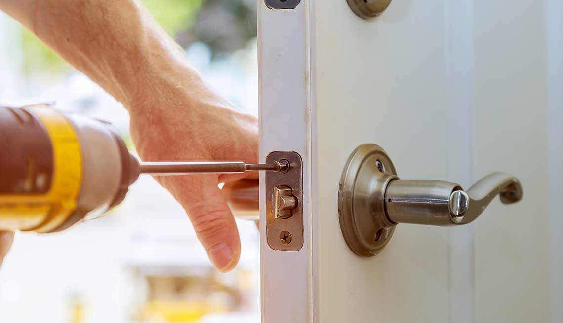 Installation locked interior door knobs, close-up wood worker hands install lock.