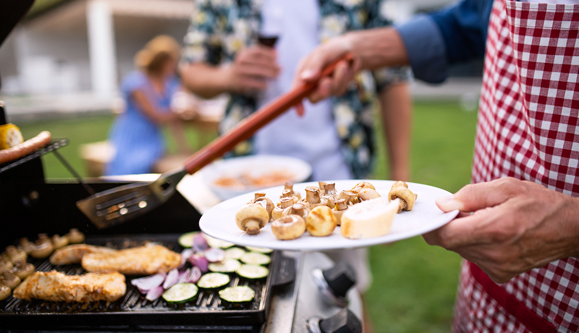 A midsection of family outdoors on garden barbecue, grilling.