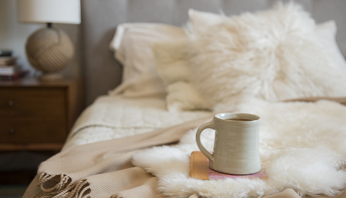 Taza de café y libro sobre una cama