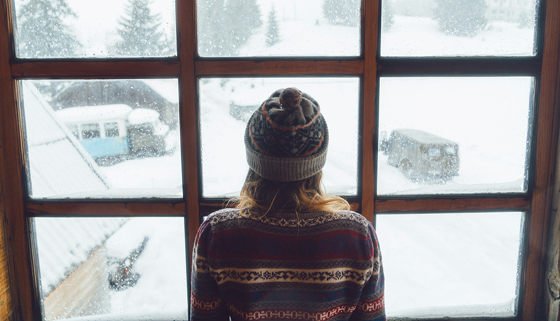 Mujer mira por la ventana en un día de invierno