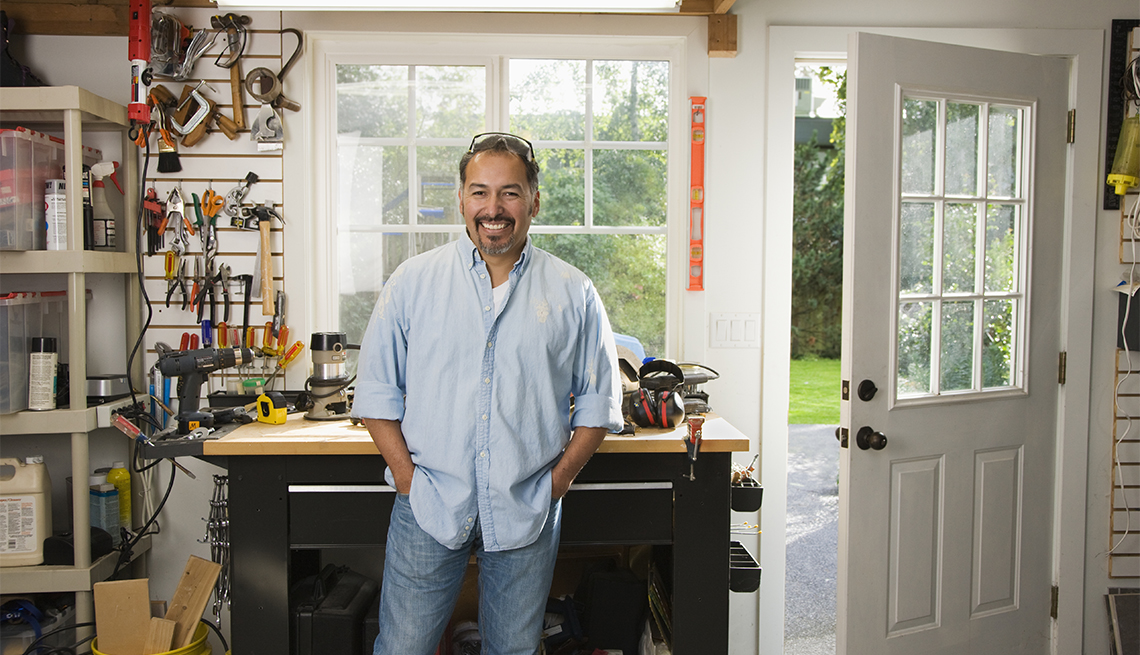 Hombre sonríe en su taller puesto en el garaje de su casa