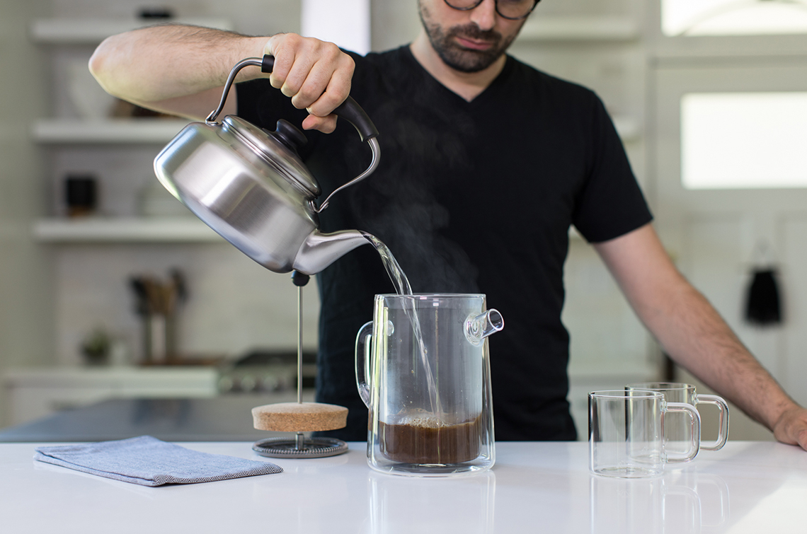 man using a french press to make coffee 