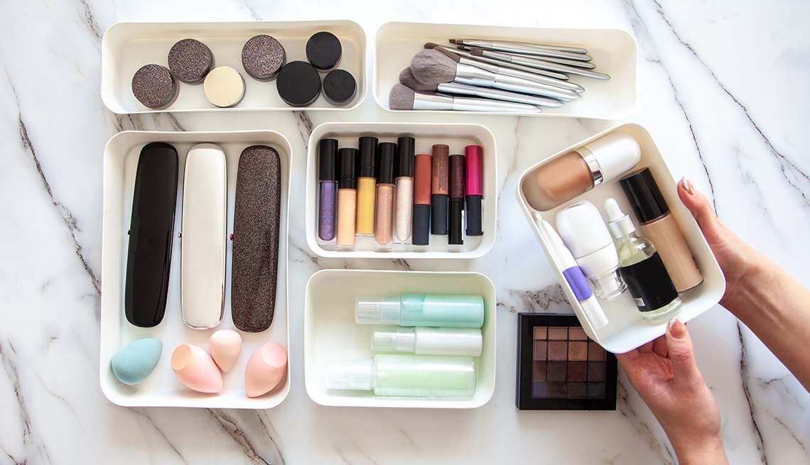 woman organizing makeup in small bins to go in a drawer