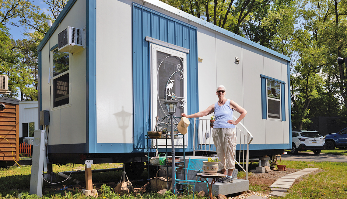 betsy barbour stands on the porch of her tiny house