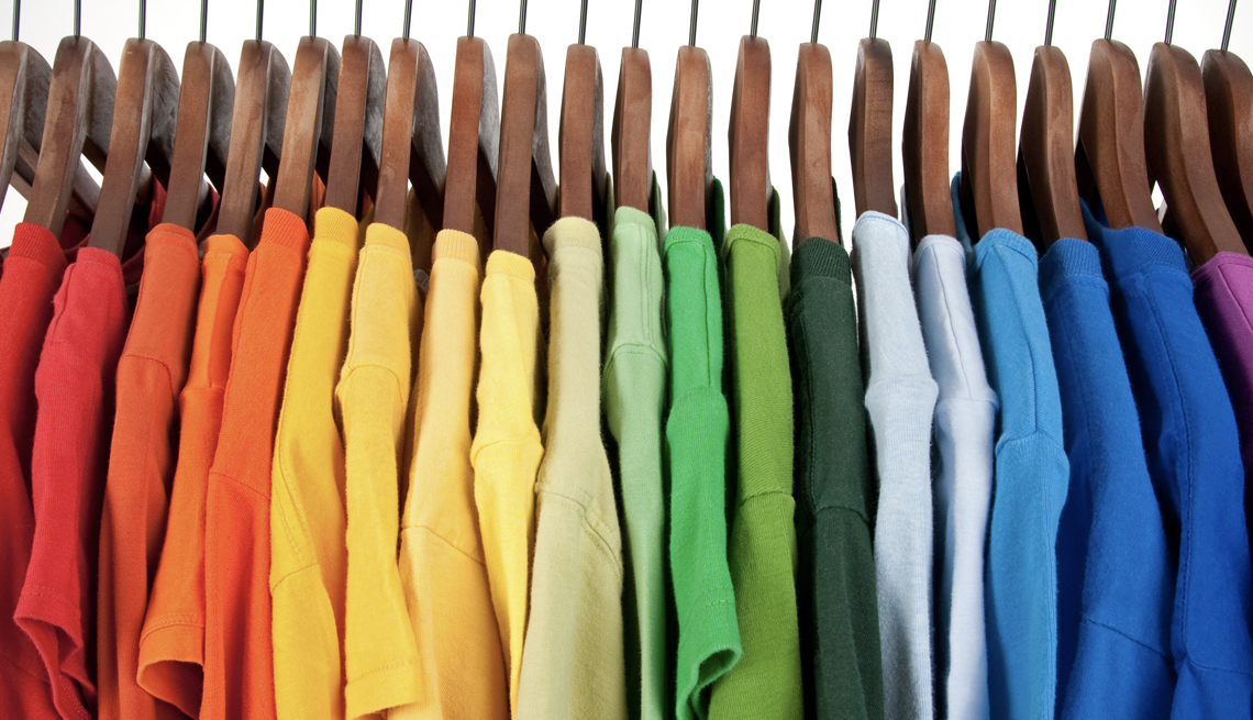Camisas colgadas en el closet organizadas por colores