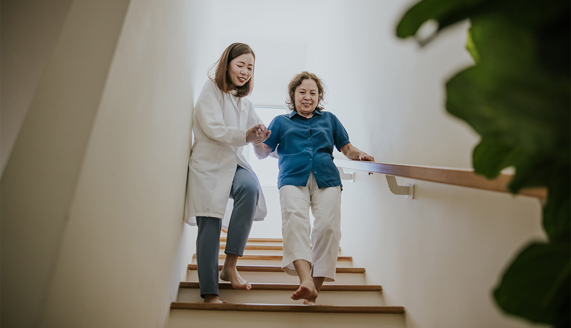 Grandmother and her female medical physiotherapist walking down the stairs