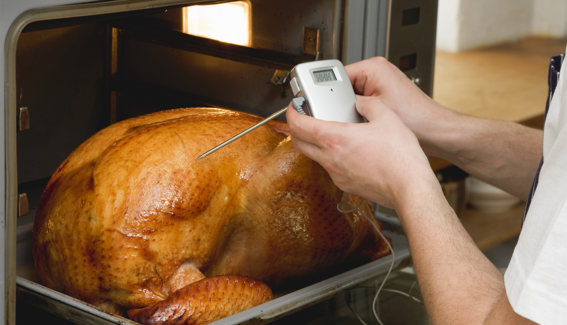 Checking turkey in oven with meat thermometer