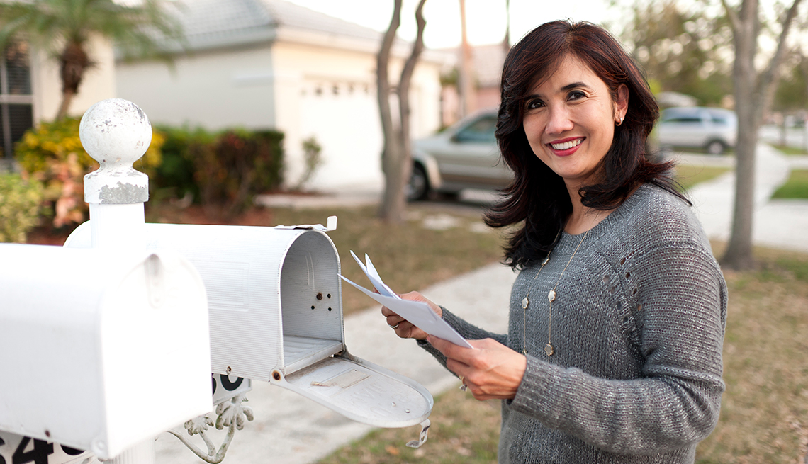 Mujer recogiendo correo de un buzón afuera de casa