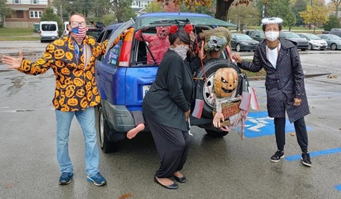 Three adults dressed in costumes for a Halloween car parade