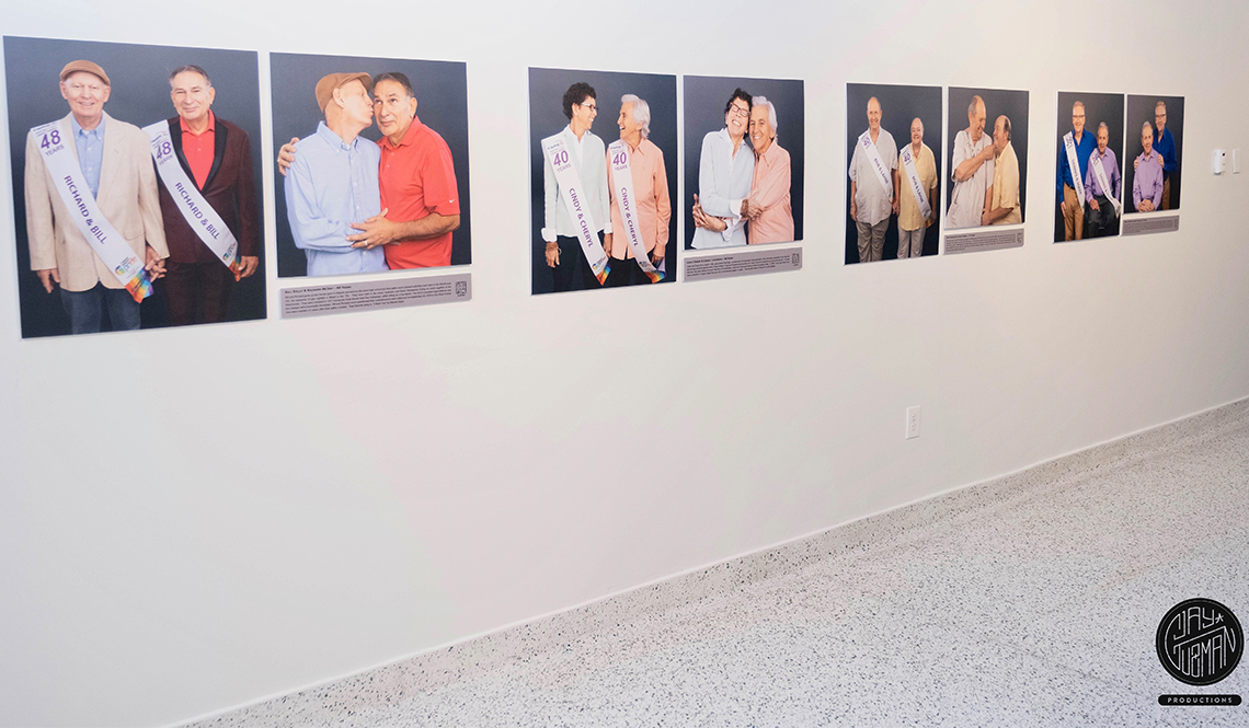 A wall display with portraits of four long-term LGBTQ+ couples