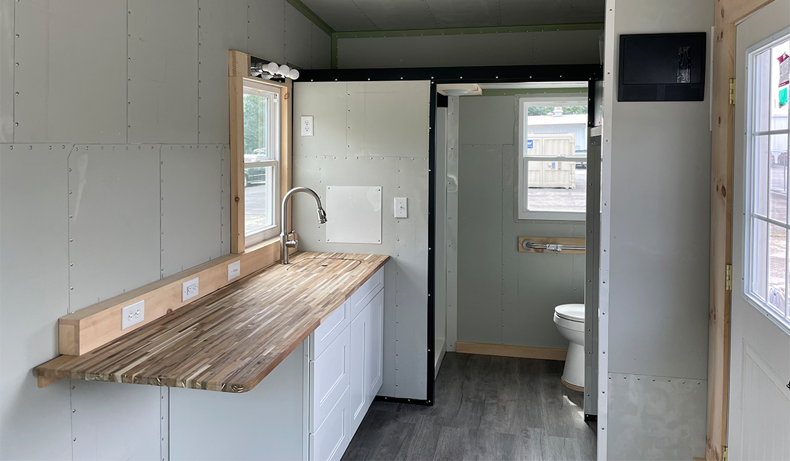 An interior view of the tiny house shows the bathroom and kitchen area