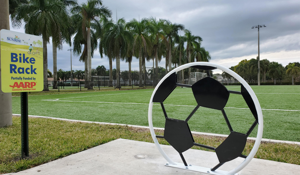 A soccer-ball themed bike rack next to a playing field