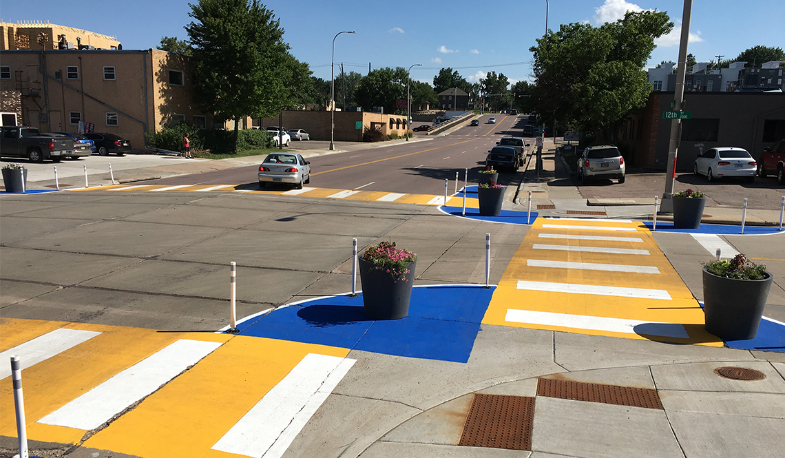 An intersection with bright yellow painted crosswalks and blue bulb-outs
