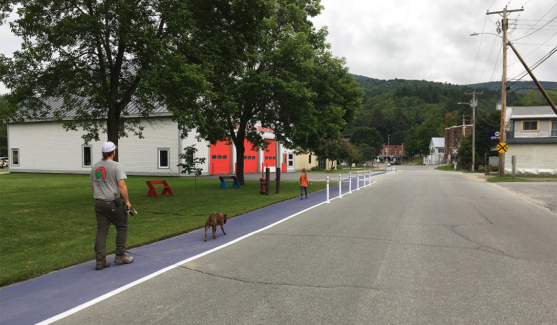 A man, dog and child walk along a painted walk-bike path