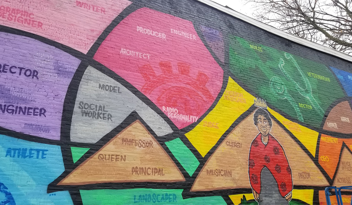 A colorful mural shows a woman wearing a crown surrounded by word naming different careers