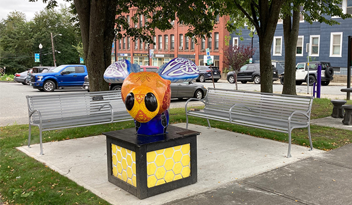 Two metal benches installed near a colorful sculpture in a spot called Fiske Park