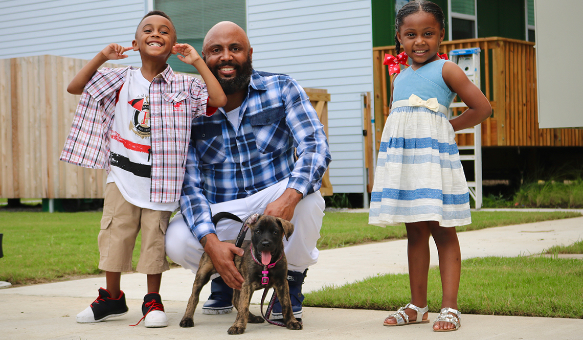 A military veteran poses with his young son, daughter and puppy in the Bastion housing community