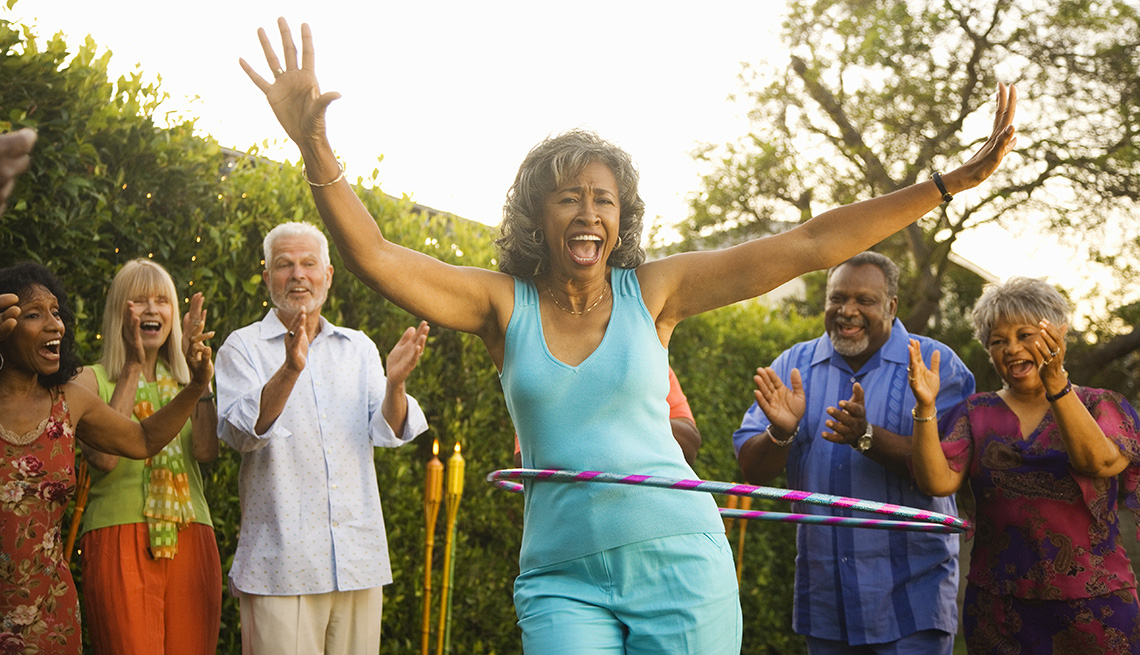 Mature African American Woman Laughs While Doing The Hula Hoop With Others Cheering Her On In The Background, Livable Communities, 8 Features Of An Age Friendly Community