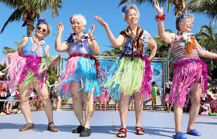 Older women in Taiwan perform on stage while wearing hula skirts