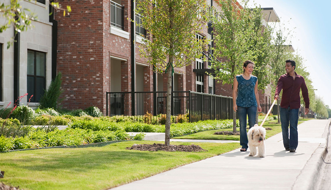 A Young Couple Walks Their Dog Past Apartment Complex, In Livable Communities Slideshow