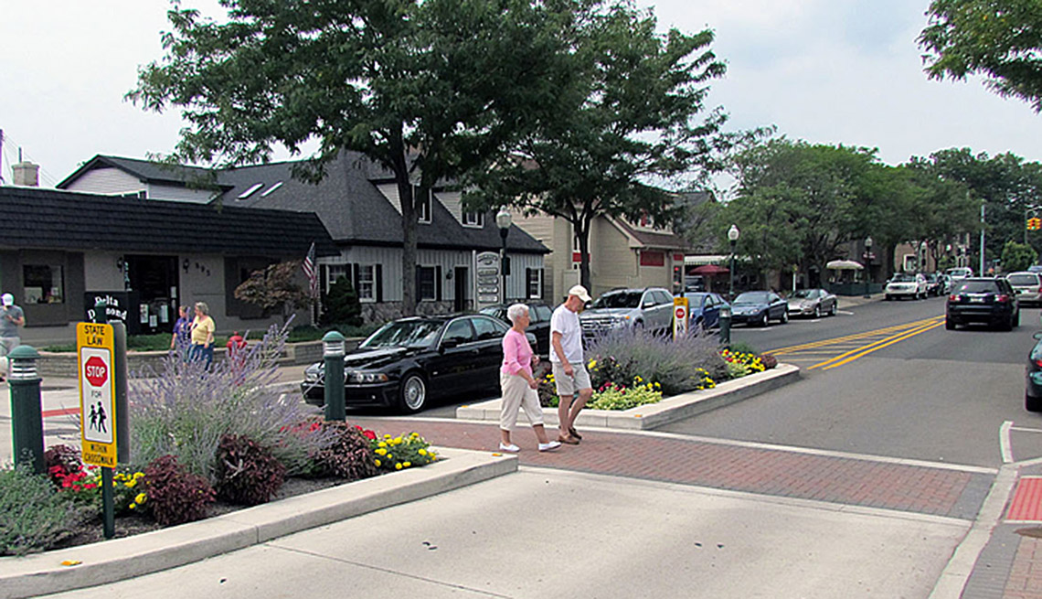 Elderly Couple Crosses A Crosswalk Through Town, Cars, In Livable Communities Slideshow