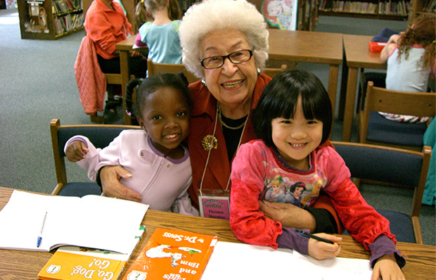 An older woman and two pre-school girls take a break from reading at a library.