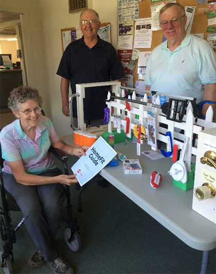 A woman and two men pose beside a display of handy household tools, including the AARP HomeFit Guide.