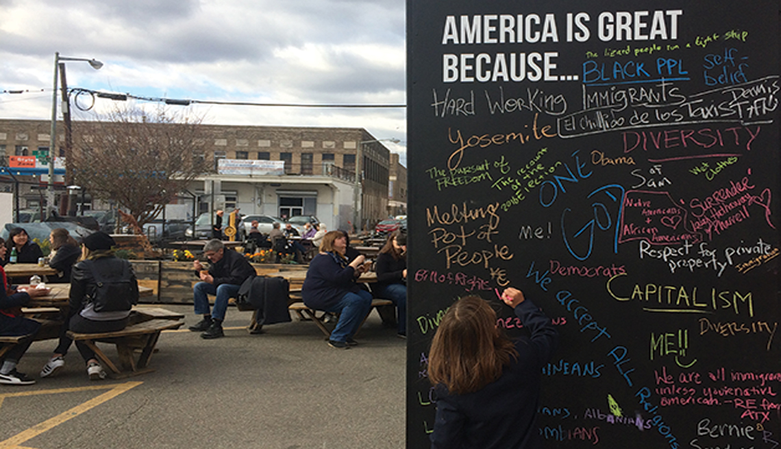 A child writes on a chalkboard that reads America is Great Because ...