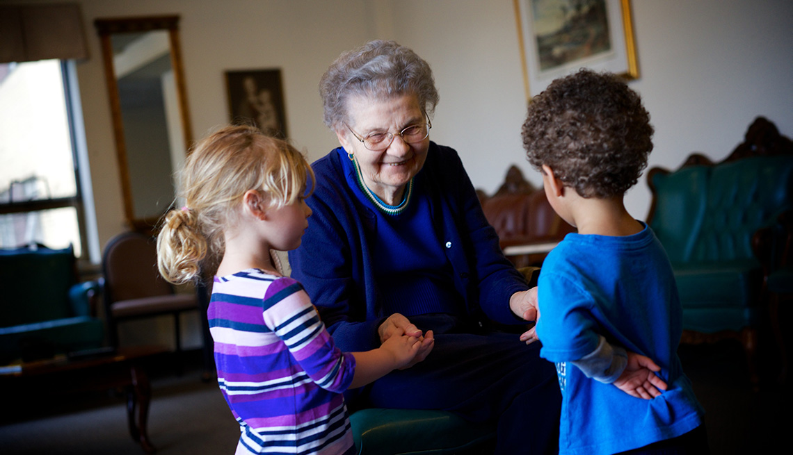Providence Mount St Vincent Assisted Living, Seattle, Elderly Woman Shakes Hands And Talks To Two Young Children, Indoors, Room, Livable Communities, Build Bonds Across Generations