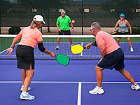 Two older men and two older women play pickleball.