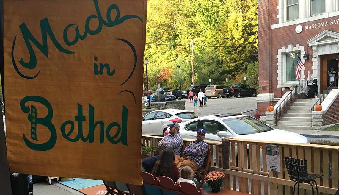 Visitors sit in a parklet that's decorated with a sign that reads Made in Bethel