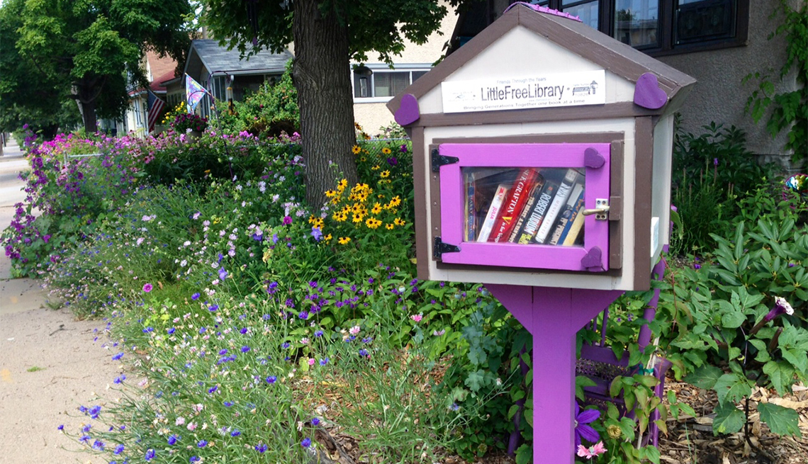 A purple Little Free Library is surrounded by wildflowers in Minneapolis.