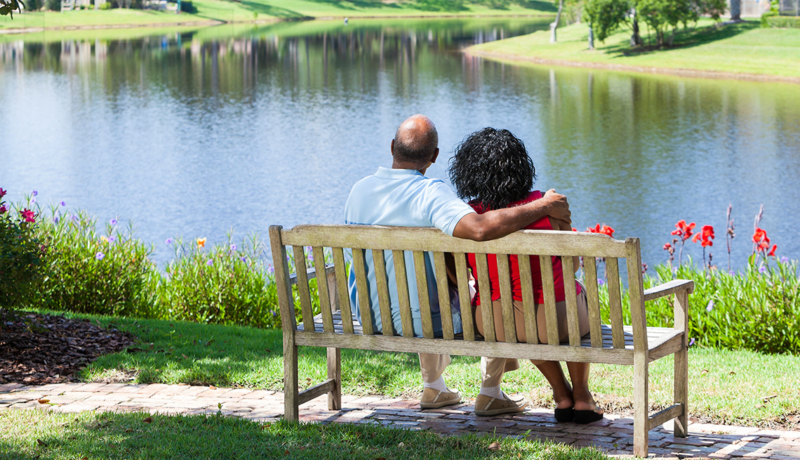 African American couple sitting together beside lake.