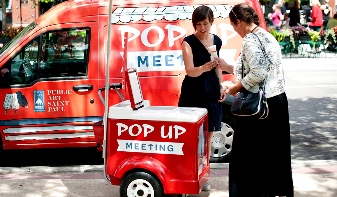A Saint Paul resident accepts a popsicle from a city staffer working the Pop Up Meeting van and mobile cooler. 