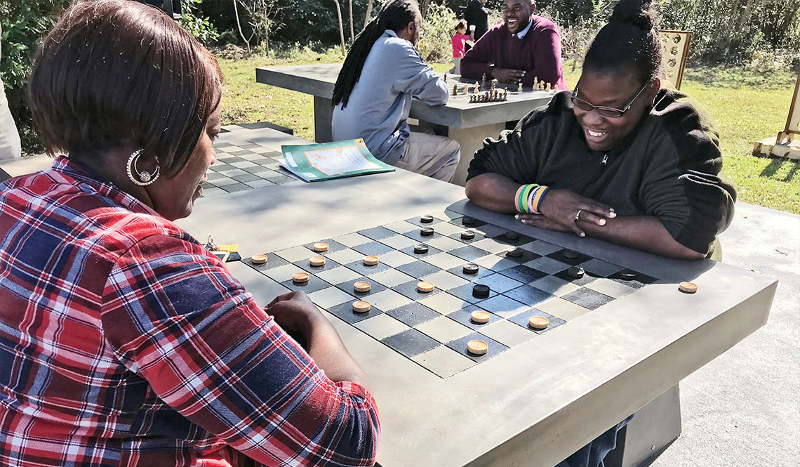 Two young women play checkers at an outdoor game table in Macon, Georgia
