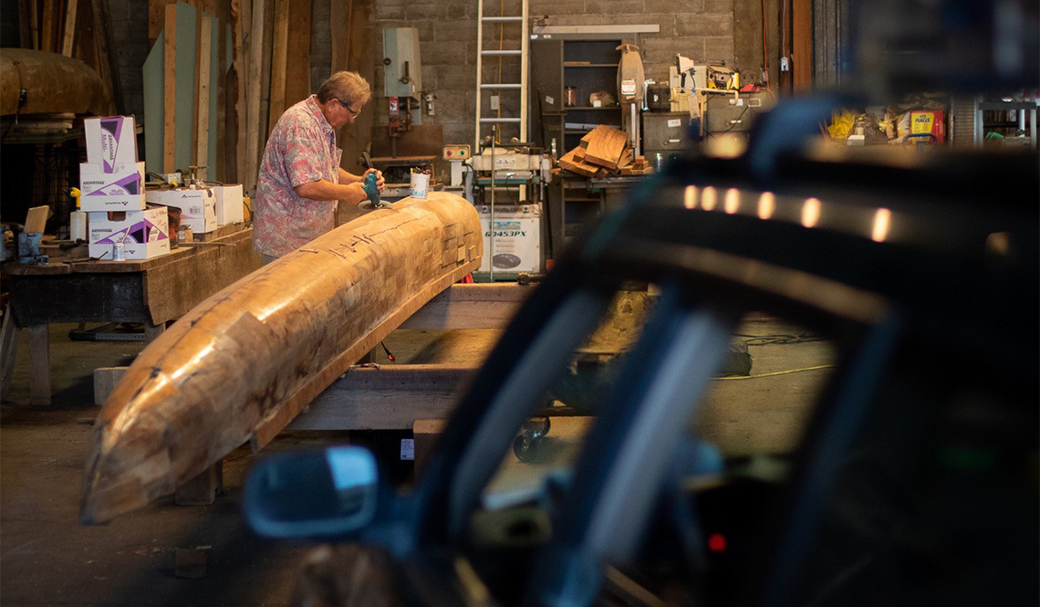 A member of a men's shed works on building a canoe