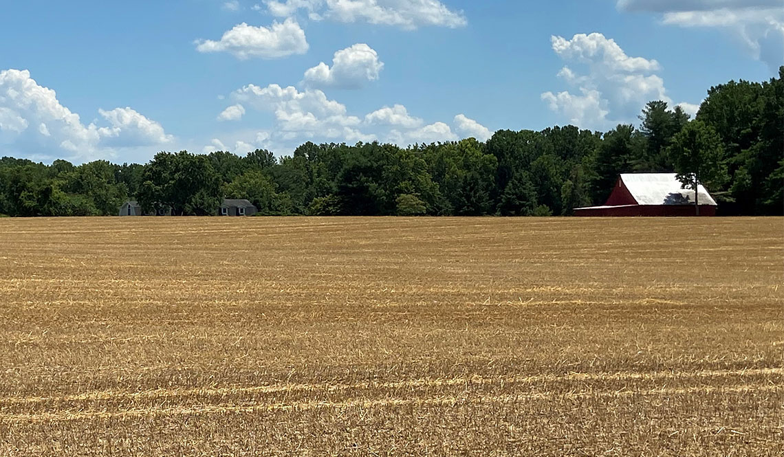 Scene of a farm field and farm house