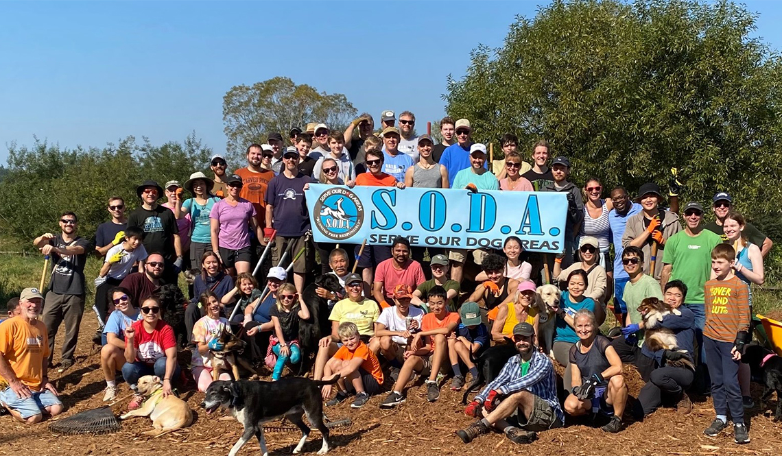 A large gathering of dog park volunteers pose for a group picture