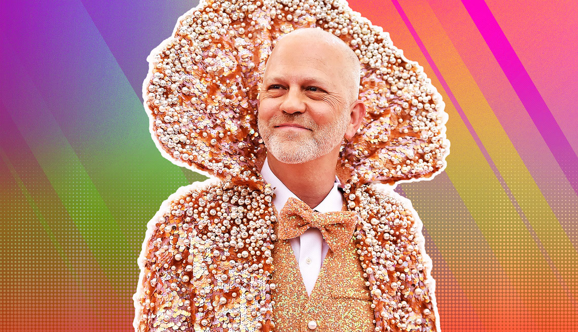 item 22 of Gallery image - Ryan Murphy wearing a sparkly vest, bowtie and jacket with very high collar above his head, silhouetted against a rainbow ombre background