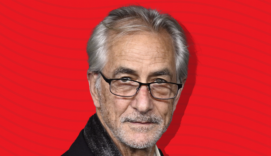 item 6 of Gallery image - david strathairn against red background with curved lines going horizontally from one end to the other