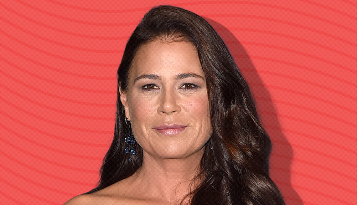 maura tierney against dark pink background with curved lines going horizontally from one end to the other