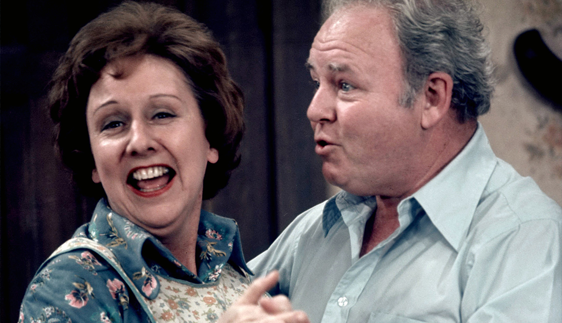 item 29 of Gallery image - Edith Bunker with a big smile standing close to Archie Bunker with one of his signature goofy facial expressions