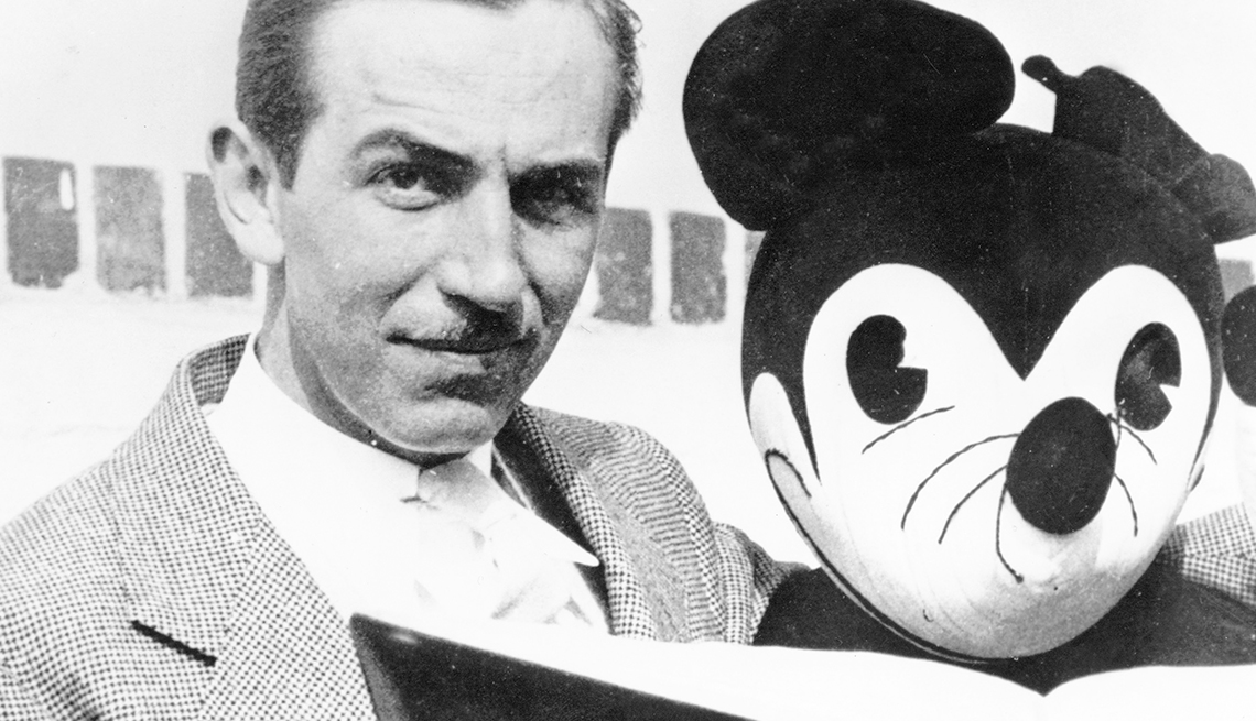 item 17 of Gallery image - Walt Disney looks at the camera while reading a book with Mickey Mouse