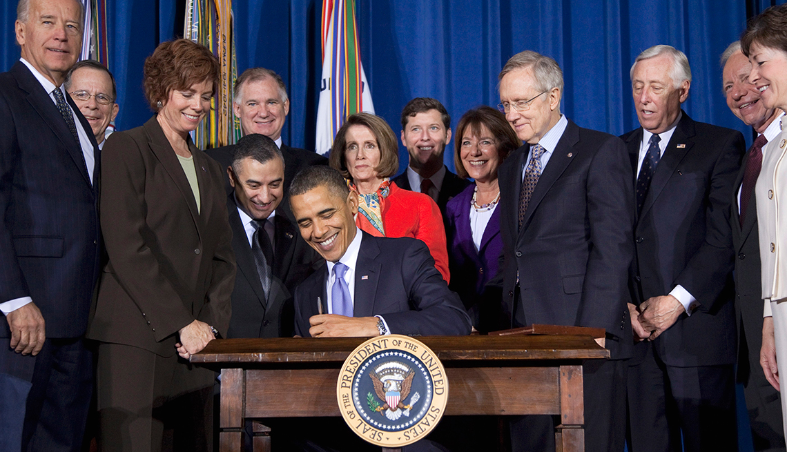 item 10 of Gallery image - A smiling President Barack Obama signs a bill while lawmakers look on