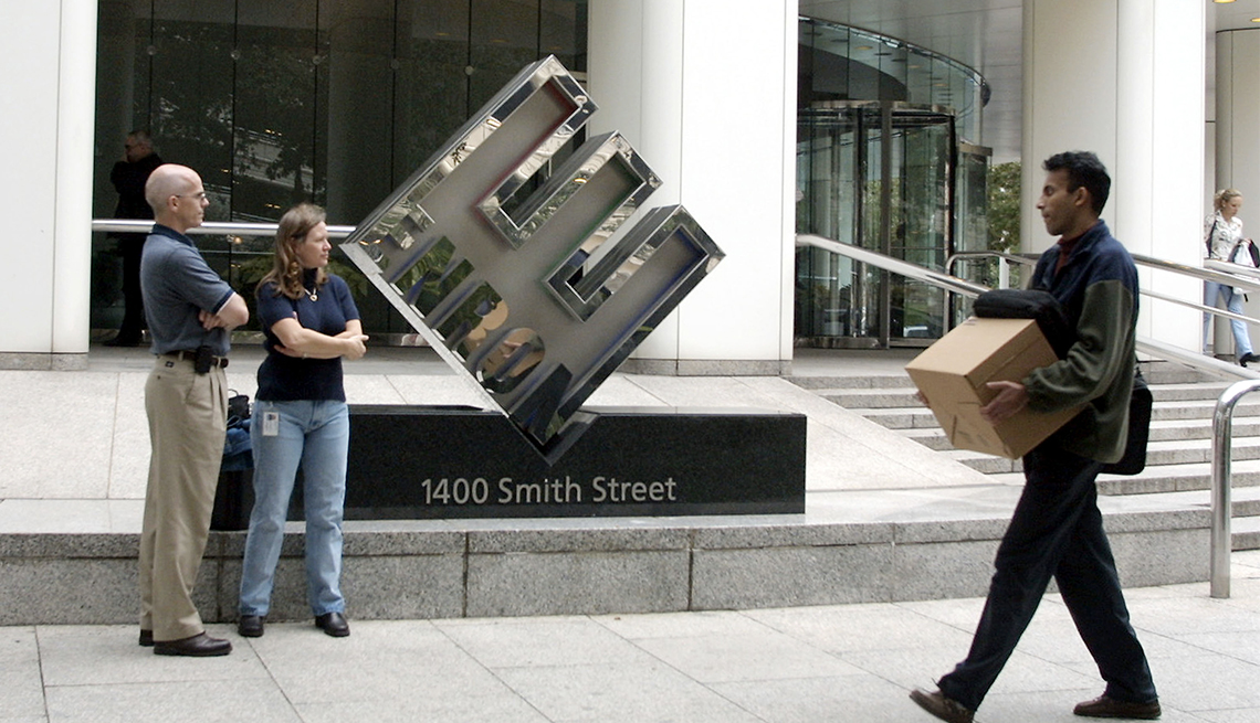 item 30 of Gallery image - Enron employee leaving company headquarters carrying a box past Enron sign '1400 Smith Street'