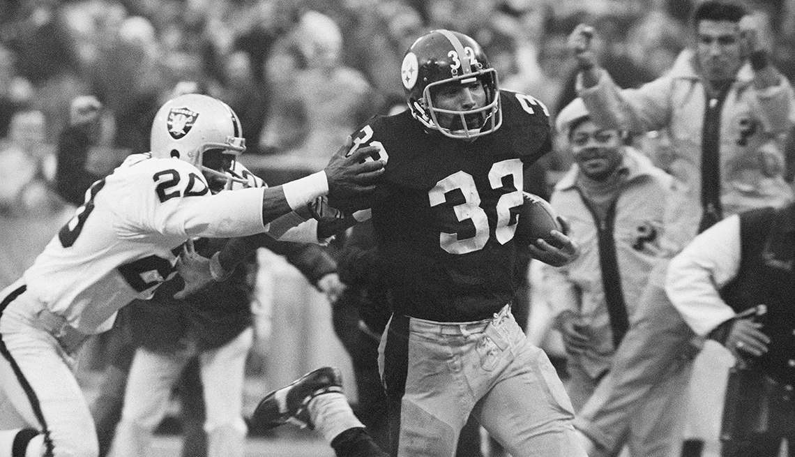 item 9 of Gallery image - Pittsburgh Steelers fullback Franco Harris runs with the football while  an Oakland Raiders player tries to tackle him and fans cheer