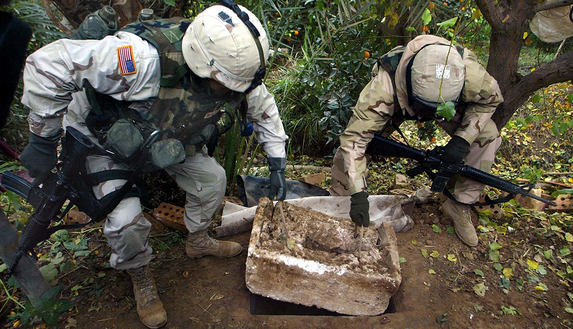 item 19 of Gallery image - two U.S. soldiers show the hole where dictator Saddam Hussein was captured